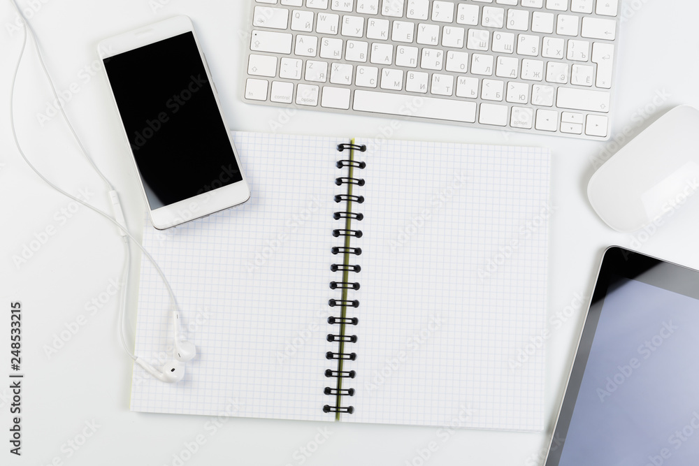 Top View of trendy White Office Desk with keyboard, white earphones and office supplies. Top View of trendy White Office Desk with keyboard, white earphones and office supplies.