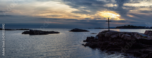 Panoramic seascape view of a cross on a rocky shore during a vibrant sunset. Taken on the Atlantic Ocean in New Haven, Connecticut, United States. © edb3_16