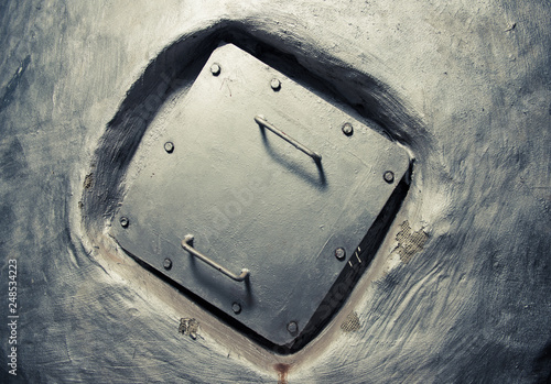 square manhole cover inside wall covered with silver paint photo