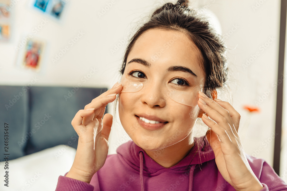 Close up of dark-eyed Asian woman taking care of her skin Close up of dark-eyed Asian woman taking care of her skin
