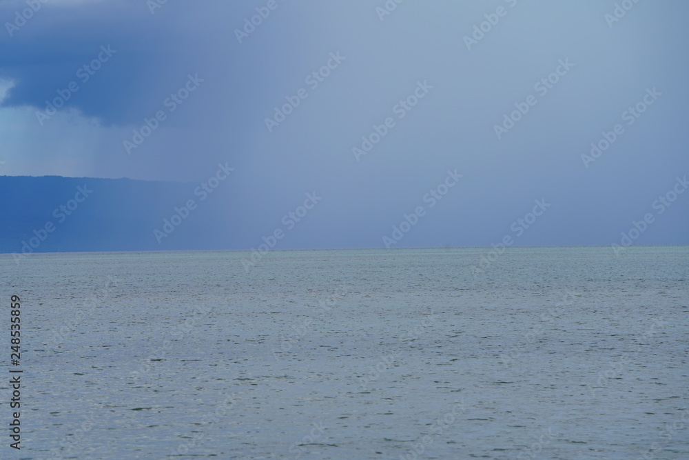 View of a storm in the distance with mountain background at Manjuyod Sandbar, Philippines