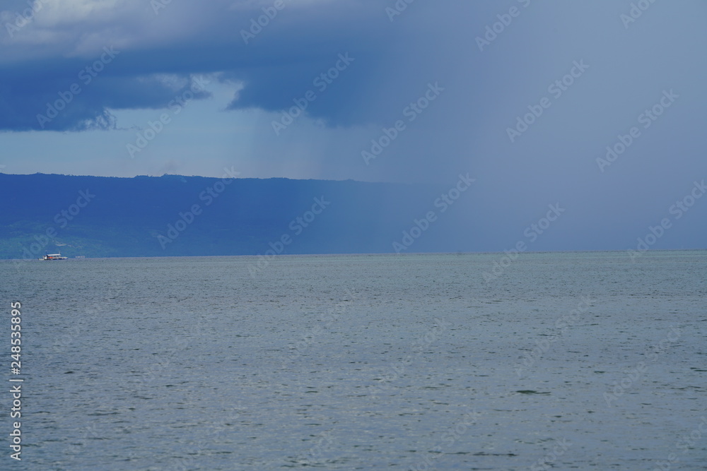 View of a storm in the distance with mountain background at Manjuyod Sandbar, Philippines