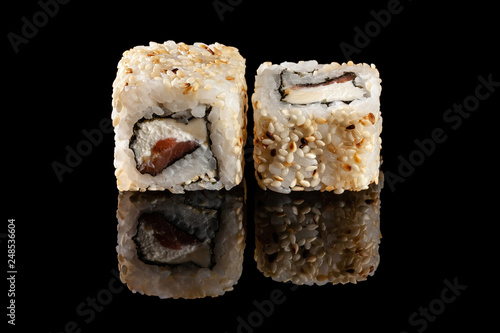 Concept of Asian cuisine. Two rolls of sushi with different fillings on a black background with the age for a Japanese menu for a cafe, restaurant, sushi bar.