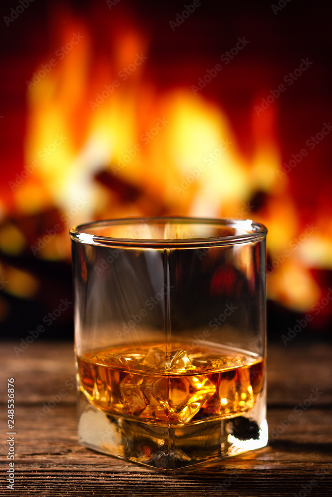 Whiskey in a glass with fire in the fireplace on the background