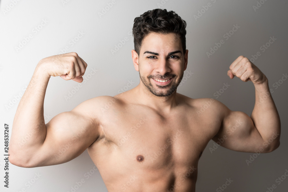 Strong attractive man posing and showing muscle looking at camera