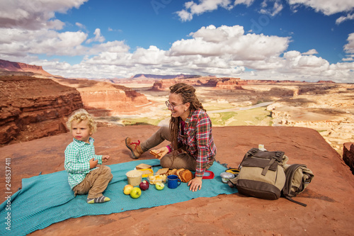 Happy mother and son having picnic while travel in nature
