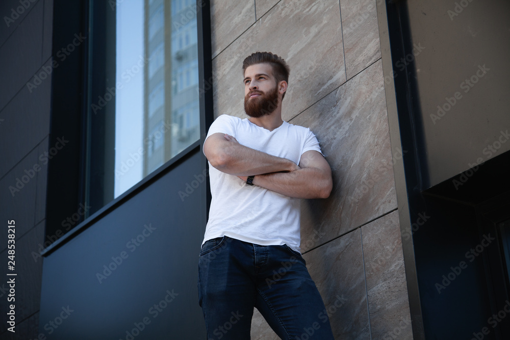 Fototapeta premium young bearded man crossed her arms over his chest against of office building
