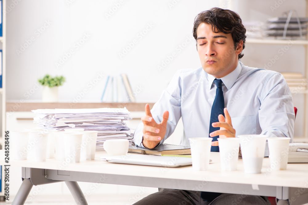 Young employee addicted to coffee Young employee addicted to coffee