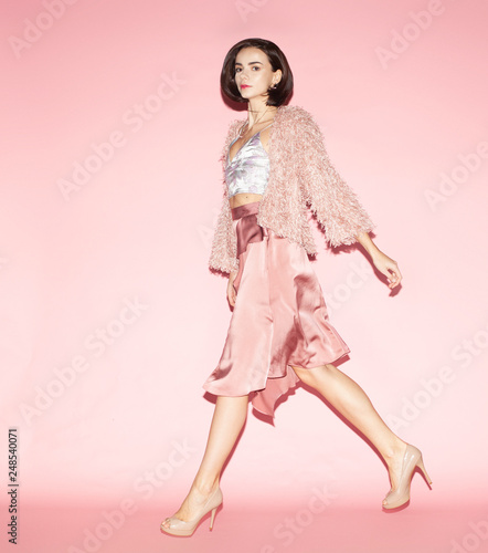 young fashion woman in pink clothes run on pink background, full lenght