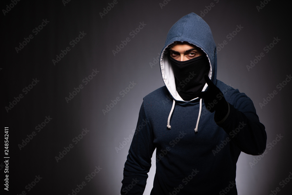 Young gangster in hood on grey background Young gangster in hood on grey background