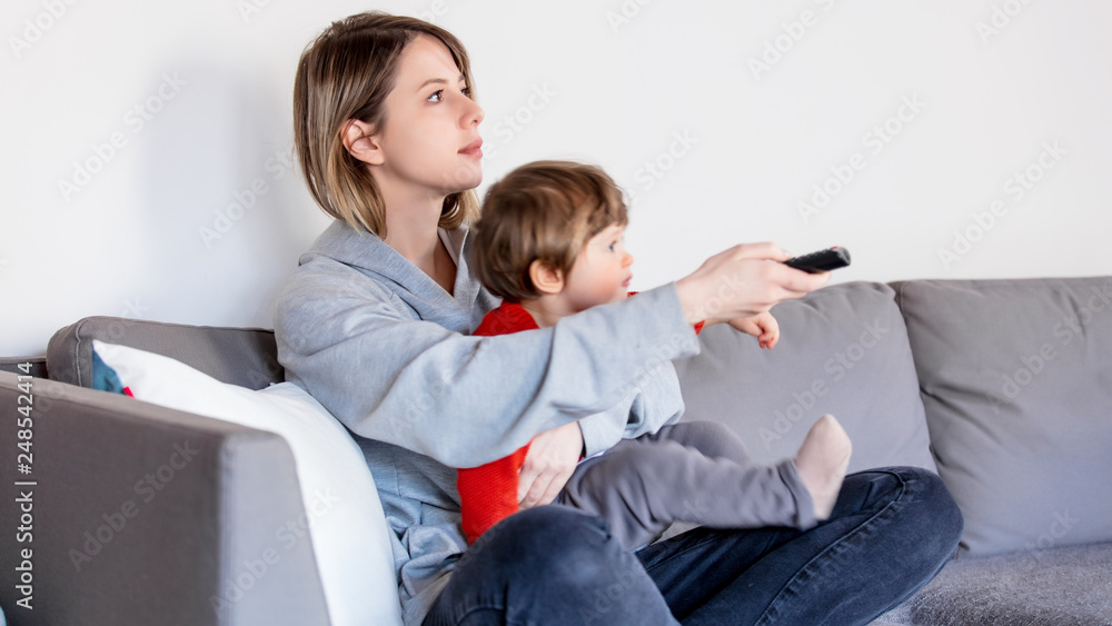 mother with son holding remote control and watching TV mother with son holding remote control and watching TV