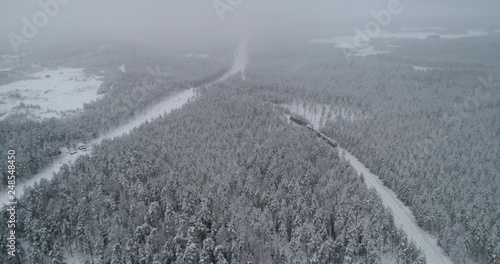 Drone shot, panning around a cargo locomotive, in a snowy scandinavian forest, in the nordic countryside, on a overcast, blizzard, winter, day, in Finland