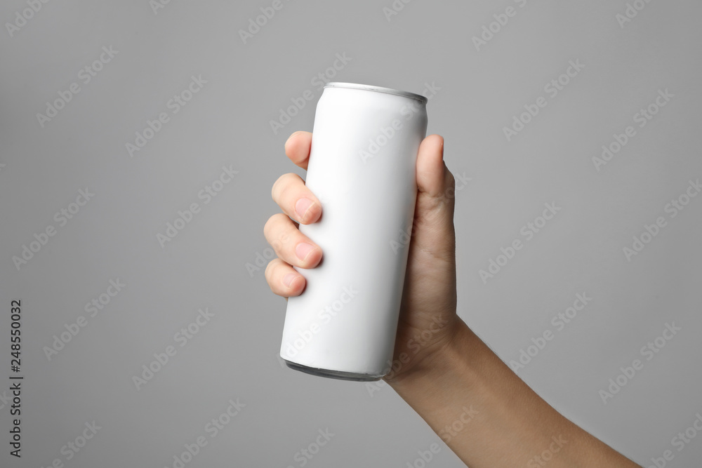 Woman holding aluminum can with beverage on grey background, closeup. Space for design Woman holding aluminum can with beverage on grey background, closeup. Space for design