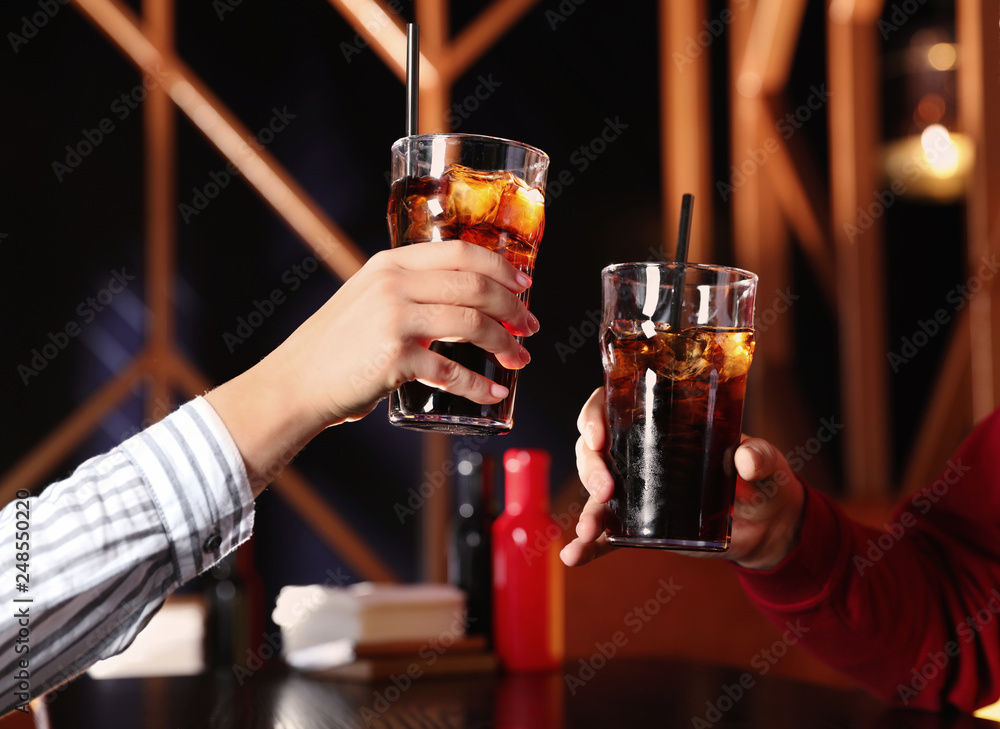 Young couple with glasses of refreshing cola at table indoors, closeup