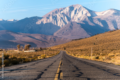 View of the Eastern Sierra Nevada mountain range in California taken in the middle of an open road/highway on a sunny autumn morning
