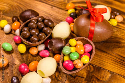 Chocolate easter eggs and multicolored candies on wooden table. Top view