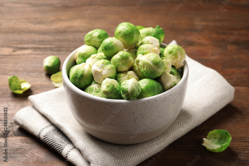 Bowl of fresh Brussels sprouts and napkin on wooden table Bowl of fresh Brussels sprouts and napkin on wooden table