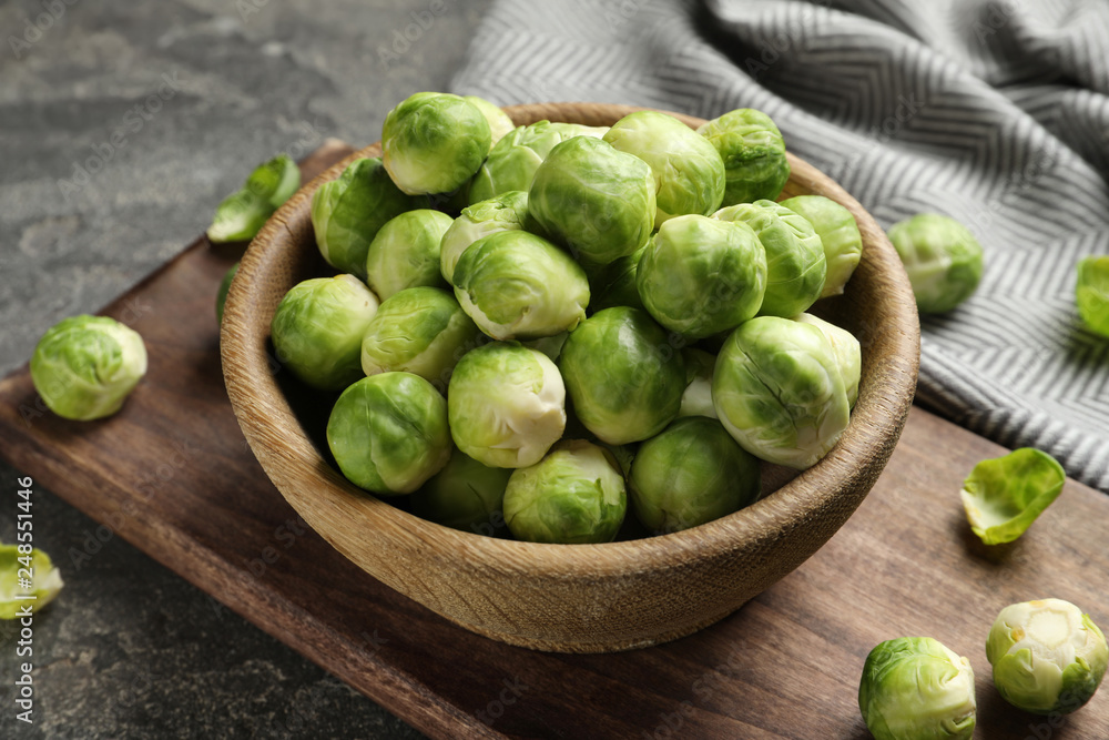 Board with bowl of Brussels sprouts on grey table Board with bowl of Brussels sprouts on grey table