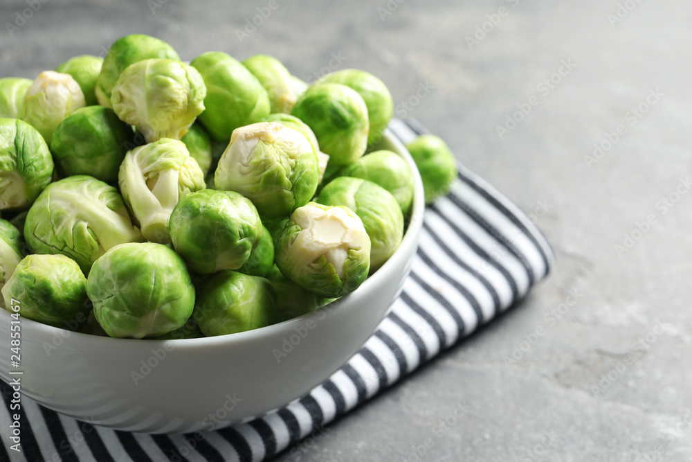 Bowl of fresh Brussels sprouts and napkin on grey table, closeup. Space for text Bowl of fresh Brussels sprouts and napkin on grey table, closeup. Space for text