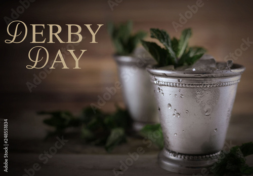 Image for Kentucky Derby in May showing two silver mint julep cups with crushed ice and fresh mint in a rustic setting photo