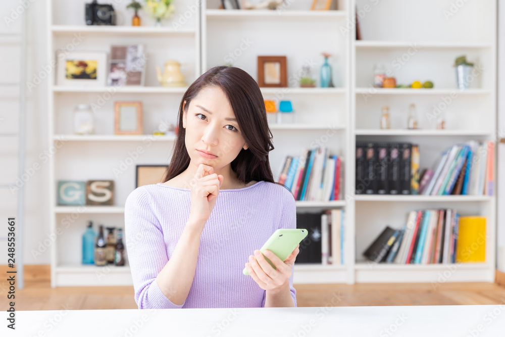 部屋でスマホを見る女性 考える 部屋でスマホを見る女性 考える