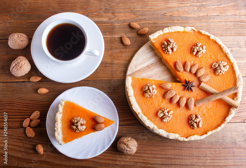 Traditional american sweet pumpkin pie decorated with nuts, on brown wooden background.