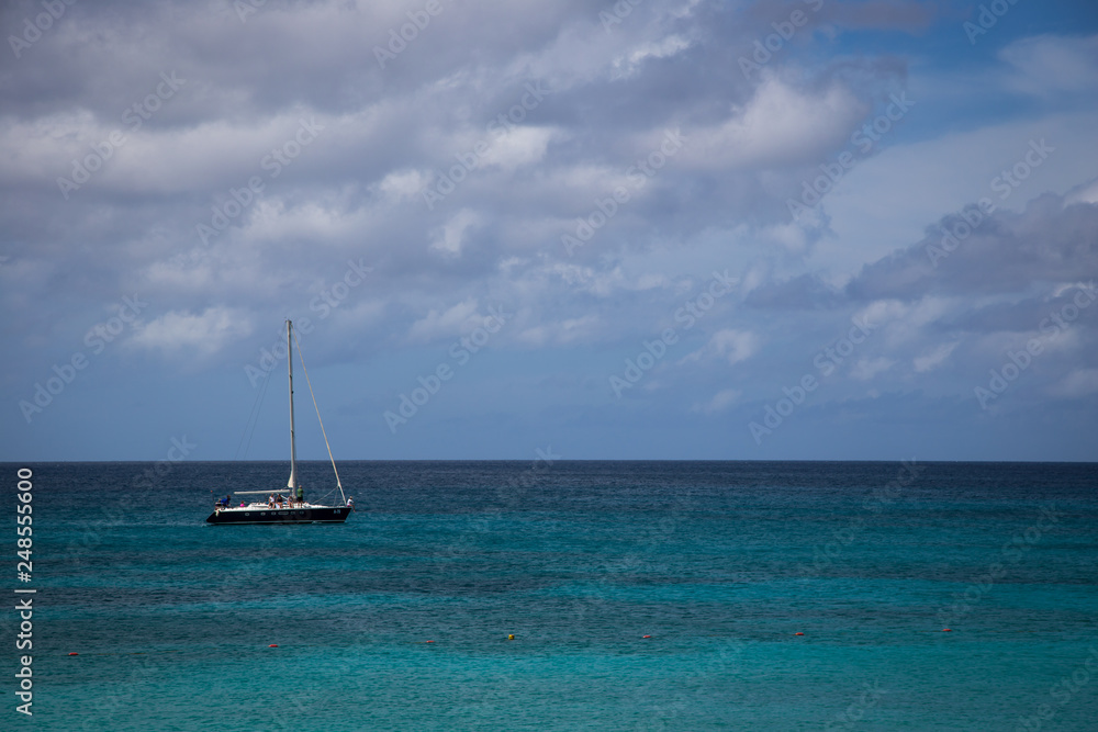 Sailboat cruising by the beach in Aruba Sailboat cruising by the beach in Aruba
