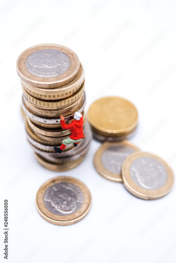 Miniature climber climbing on the stack of coins Miniature climber climbing on the stack of coins