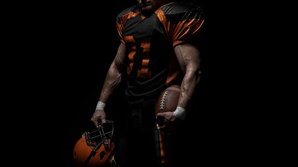 American football player on a dark background in black and orange equipment.