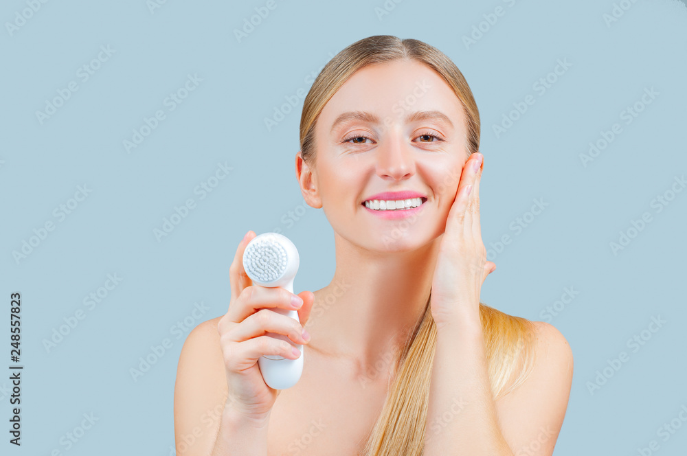Beautiful woman is washing face skin with brush.