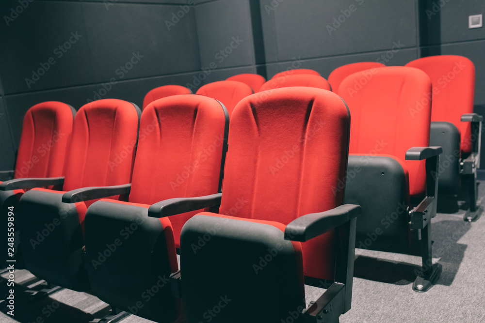 Obraz premium Cinema or movie auditorium with empty red seats or chairs