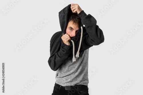 Sleepy caucasian young man slowly removes his clothes after long and busy day. Isolated on white background.