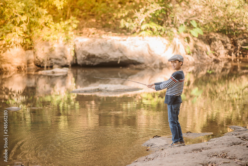 Little Asian boy fishing at the river vintage retro