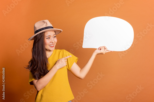 Young Asian woman show text box, speech bubble and copy space over orange background, empty space for text and ads, studio light photo