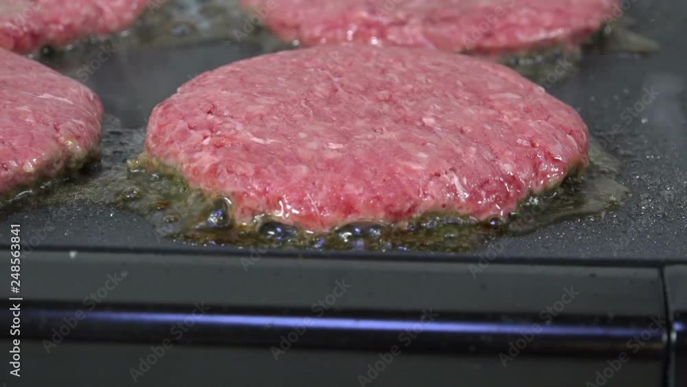 Closeup of a burger sizzling on a grill Closeup of a burger sizzling on a grill