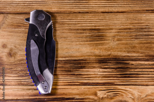 Closed folding knife on a wooden table. Top view