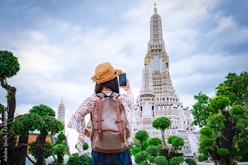 Asian woman tourists are taking photos With a smartphone at the Wat Arun temple on vacation Bangkok Thailand.