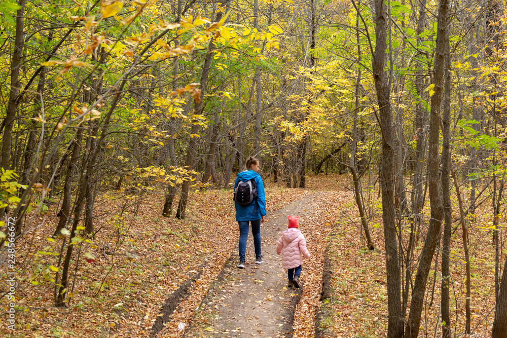 Mother and daughter are walking in the autumn forest Mother and daughter are walking in the autumn forest
