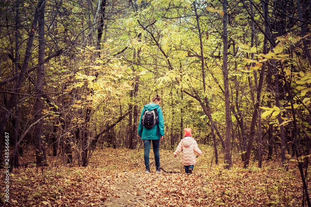 Fototapeta premium Mother and daughter are walking in the autumn forest