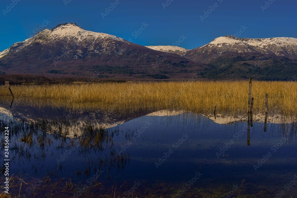 se reflejan las montañas nevadas en un lago de aguas transparentes