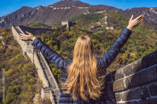 Happy cheerful joyful tourist woman at Great Wall of China having fun on travel smiling laughing and dancing during vacation trip in Asia. Girl visiting and sightseeing Chinese destination photo