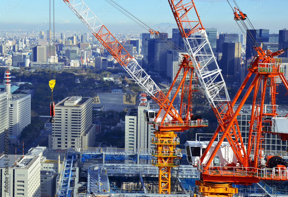 Tower Cranes on top of skyscraper with city background, a popular sight with the recent renovation and construction boom ahead of the 2020 Olympics, Tokyo Japan