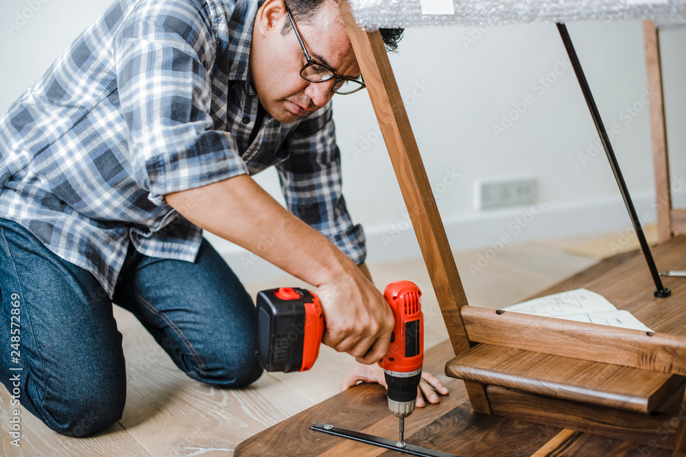 Fototapeta premium Man using hand drill to assemble a wooden table