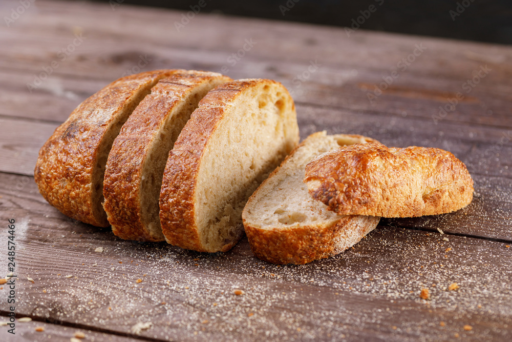 Sliced craft rye bread on a wooden table close-up on a dark background. The concept of healthy food and traditional bakery.