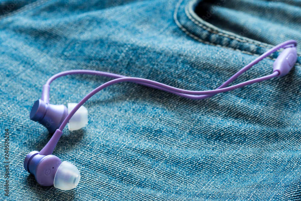 Purple earphones stick out of jeans pocket Purple earphones stick out of jeans pocket
