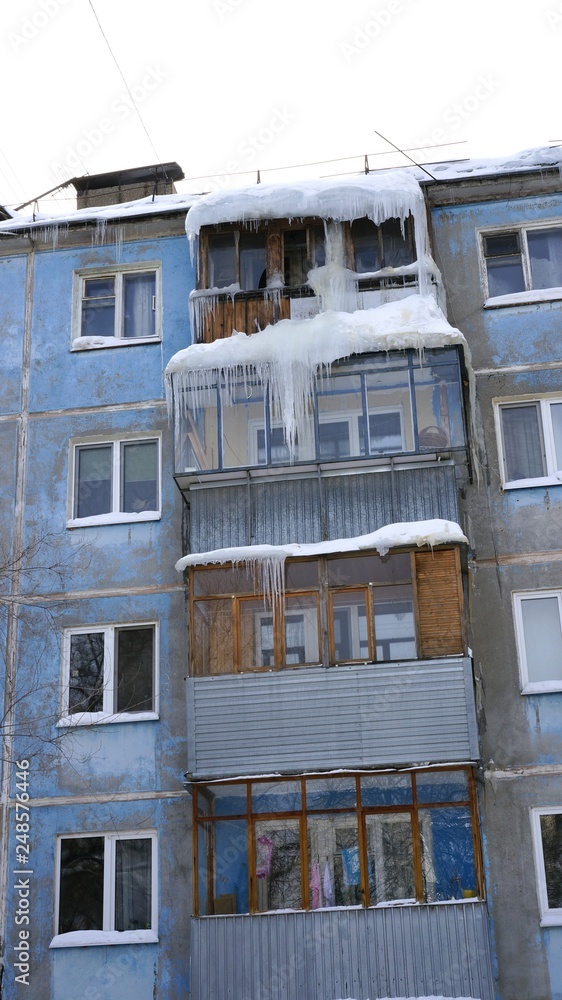 icicles on the roof and balconies of a house in winter in Russia
