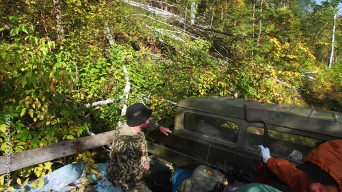 Tourists travel through russian Reserve forest in truck. Fallen trees and bushes photo