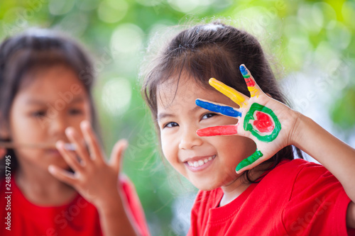 Cute asian little child girl with painted hands smiling with fun and happiness