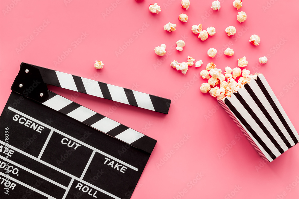 Film watching concept. Clapperboard and popcorn on pink background top view