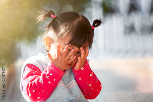 Foto Cute asian baby girl closing her face and playing peekaboo or hide and seek with
